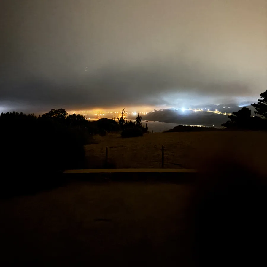 Golden Gate Bridge lights glowing beneath nighttime fog